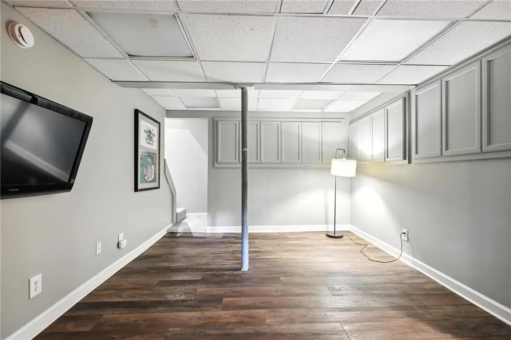 Basement with a paneled ceiling and wood finished floors