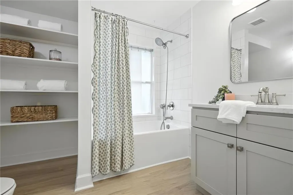 Full bathroom with vanity, shower / tub combo, and wood finished floors