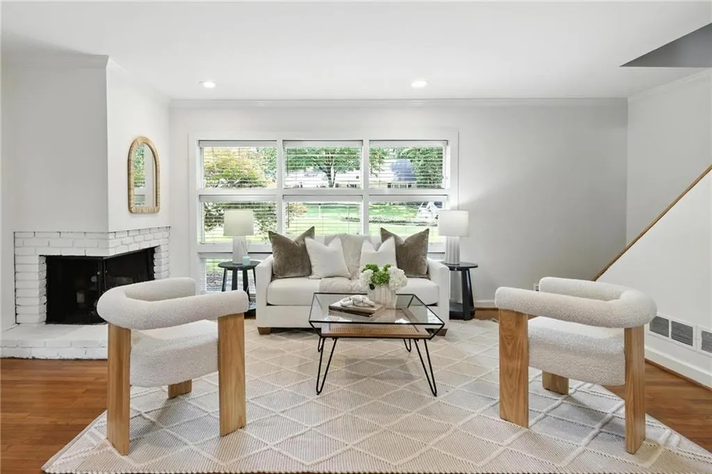 Living area with ornamental molding, light wood-type flooring, plenty of natural light, a brick fireplace, and recessed lighting
