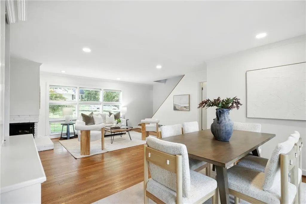 Dining area with recessed lighting, light wood-style flooring, crown molding, a brick fireplace, and stairs