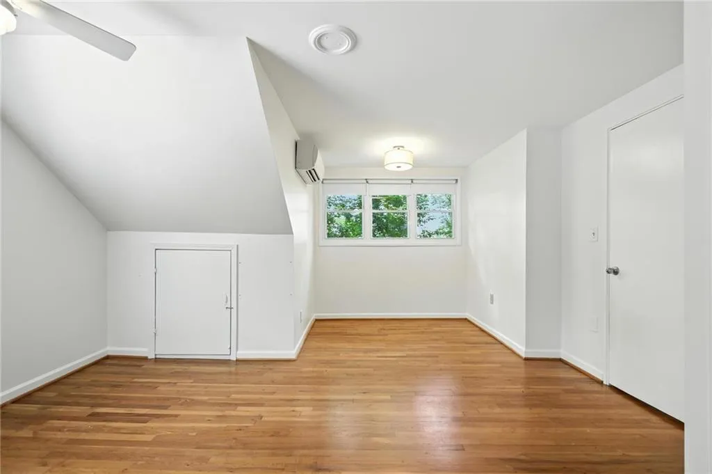 Bonus room with a wall mounted air conditioner, wood finished floors, lofted ceiling, and a ceiling fan