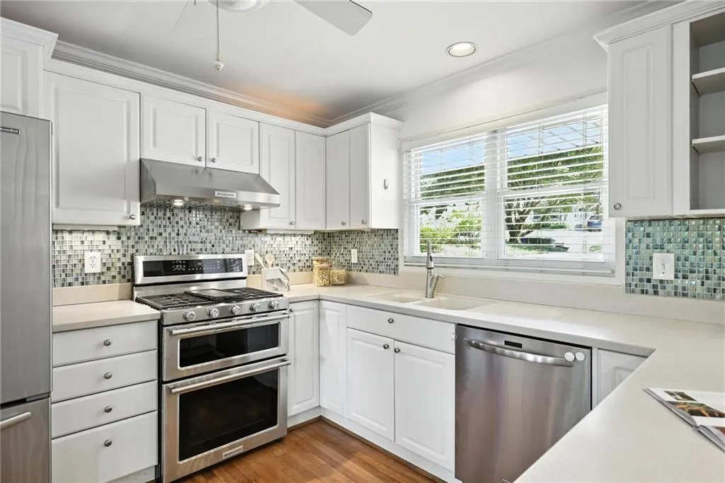 Kitchen featuring stainless steel appliances, under cabinet range hood, open shelves, ornamental molding, and white cabinetry