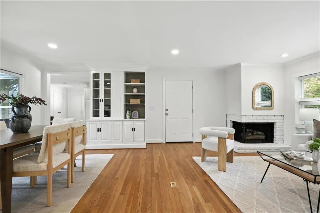 Living room with crown molding, a fireplace, light wood-style flooring, and recessed lighting