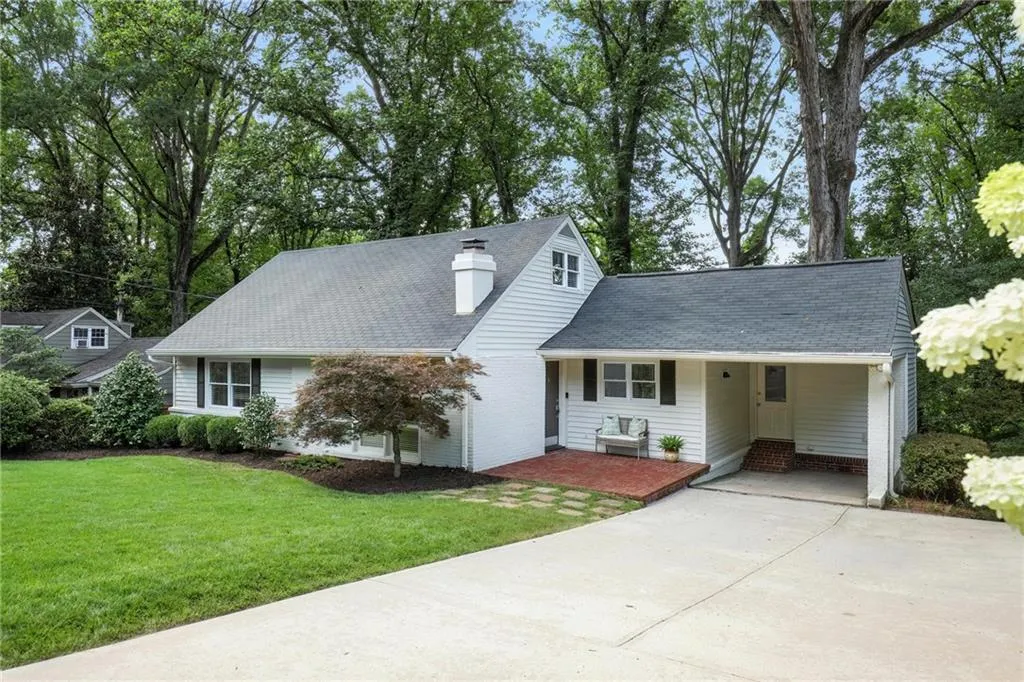 View of front of property with concrete driveway, a front yard, a chimney, and a carport