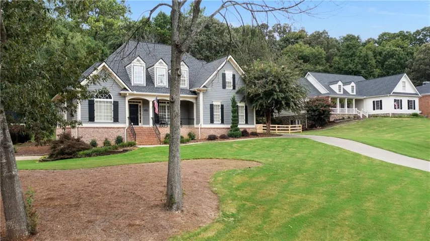 Traditional-style residence featuring a prominent front porch, dark shutters, and a brick foundation