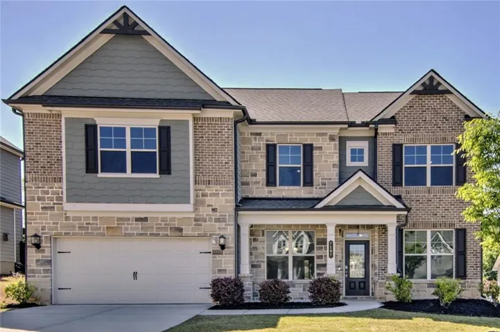 Two-story residence featuring a combination of brick and stone facade, gabled rooflines, and a covered front entry
