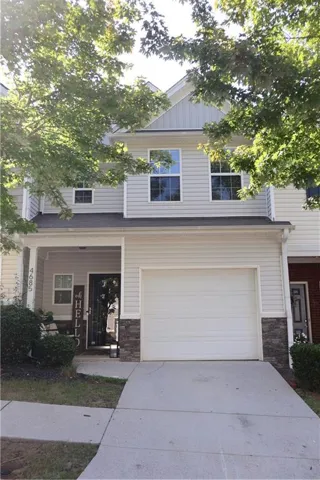 Two-story exterior with light-colored siding, partial stone veneer, and a white garage door