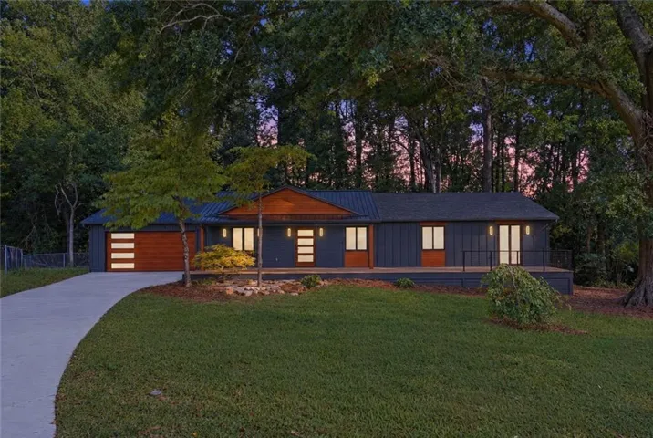 Sleek exterior featuring vertical siding, a metal roof, and a wood-finish garage door