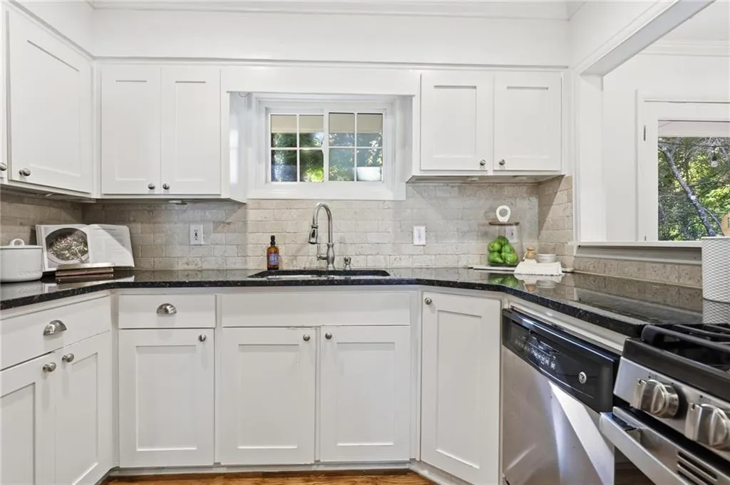 Kitchen with plenty of natural light, white cabinets, appliances with stainless steel finishes, and backsplash