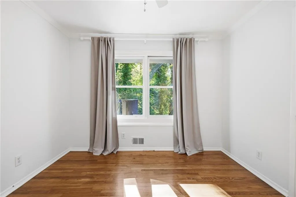 Spare room with wood finished floors, ceiling fan, and crown molding