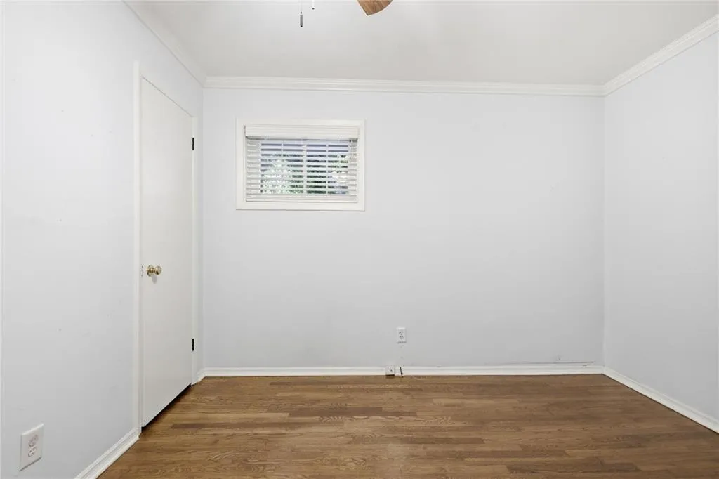 Unfurnished room with dark wood-style flooring, ceiling fan, and ornamental molding