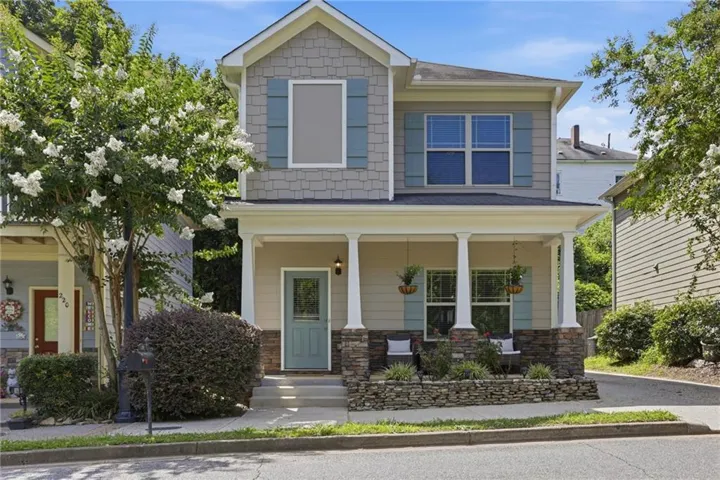 Two-story residence featuring a covered front porch with white columns, stone accents, and a light blue entry door