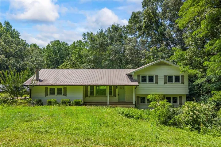 Split level home featuring a porch, a metal roof, and a front lawn