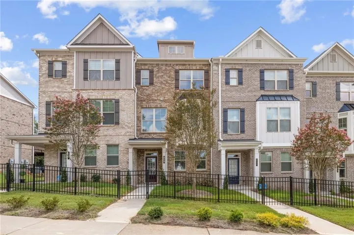 Brick facade townhome with board and batten accents, black-framed windows, and a covered entry
