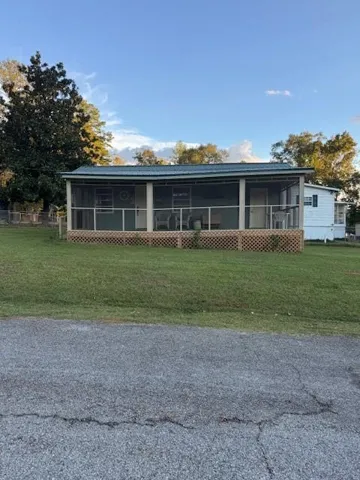 View of front of home with a sunroom, a front lawn, and a metal roof