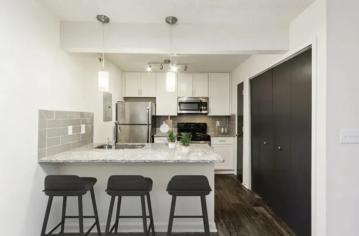 Kitchen featuring backsplash, light stone countertops, stainless steel appliances, and white cabinets