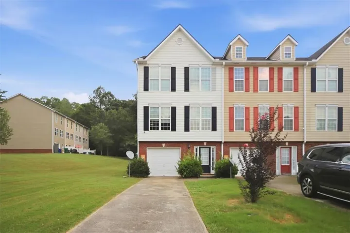 Multi-story townhome with a white siding facade, black shutters, and an integrated single-car garage