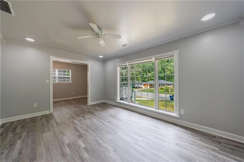 Unfurnished room with wood finished floors, visible vents, a ceiling fan, and ornamental molding