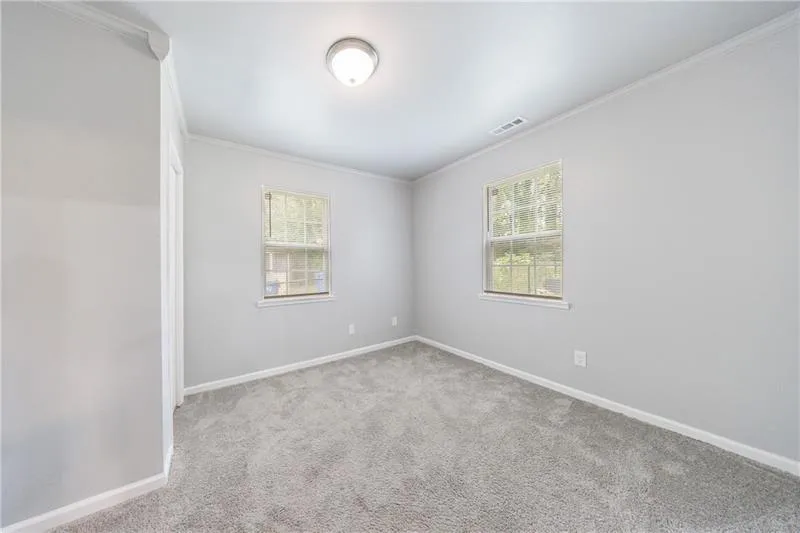 Bedroom with ornamental molding, visible vents, carpet, and baseboards