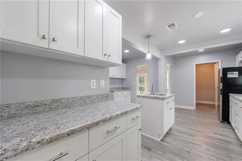 Kitchen with white cabinetry, light wood-type flooring, recessed lighting, and a sink