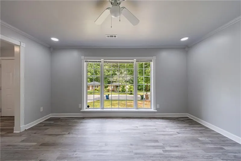 Unfurnished room with wood finished floors, visible vents, crown molding, and baseboards
