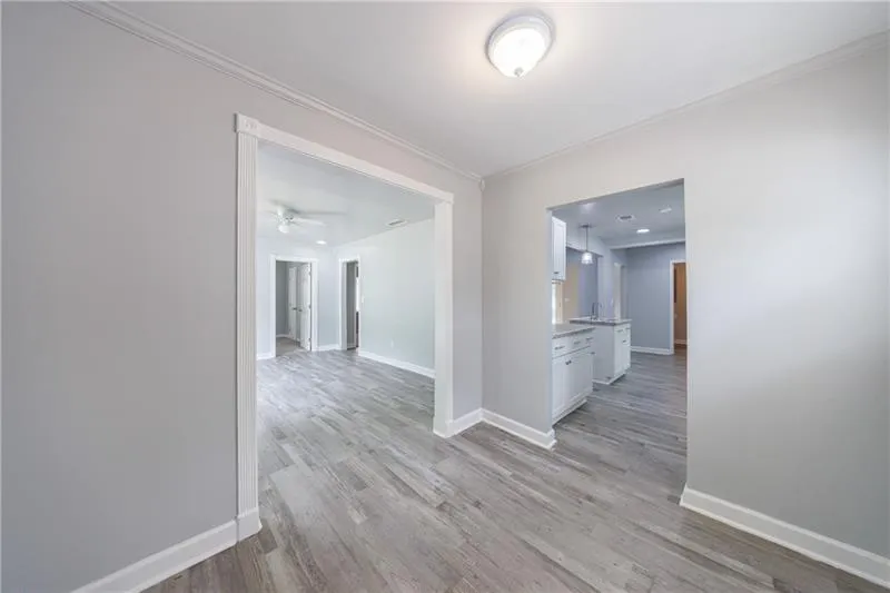 Corridor featuring crown molding, light wood-style flooring, and baseboards