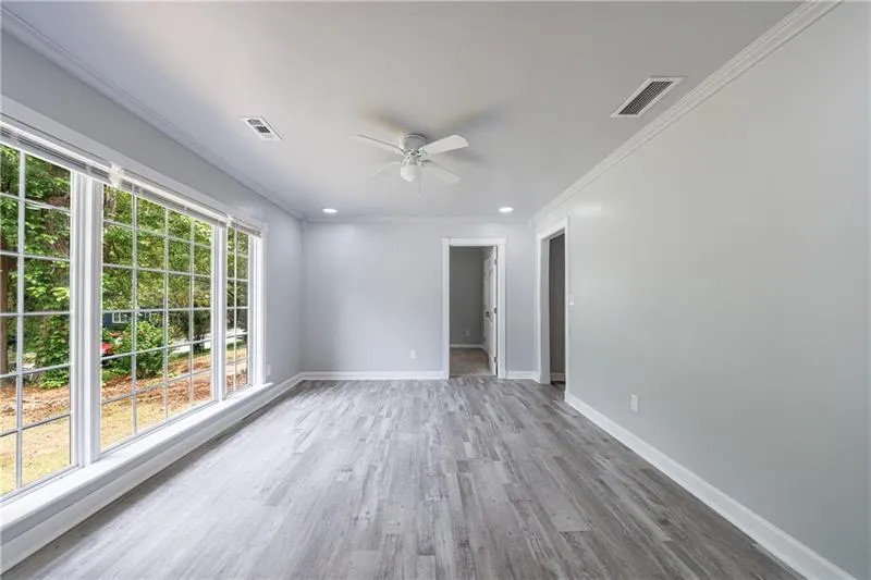 Empty room with wood finished floors, visible vents, ceiling fan, and baseboards