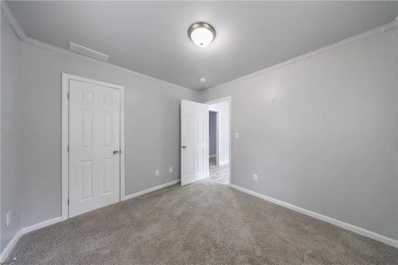 Unfurnished bedroom featuring baseboards, visible vents, ornamental molding, and carpet floors