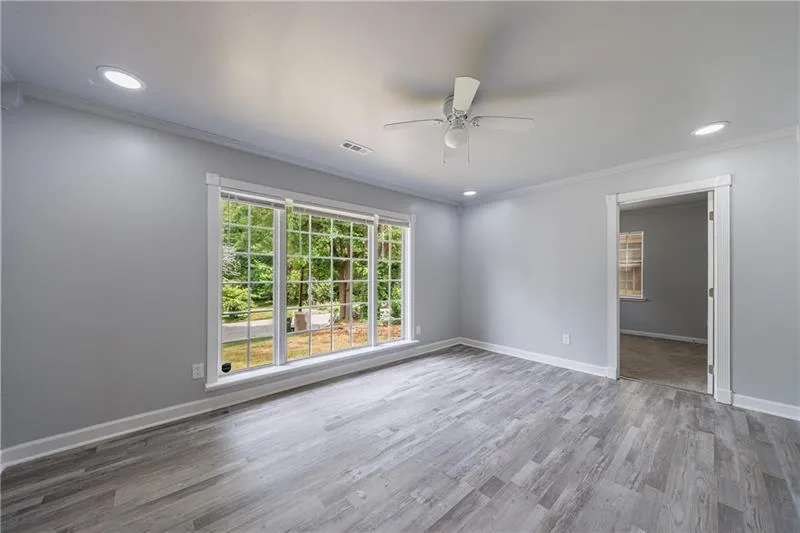 Spare room with wood finished floors, ornamental molding, ceiling fan, baseboards, and visible vents