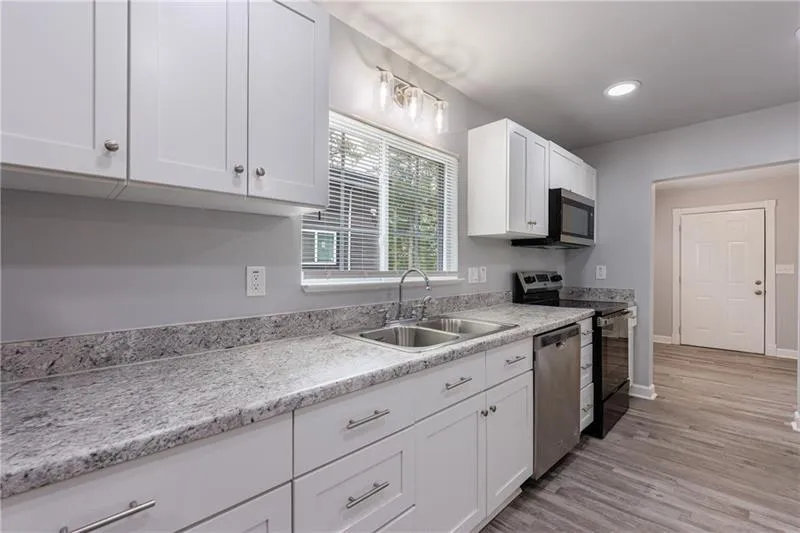 Kitchen featuring recessed lighting, appliances with stainless steel finishes, white cabinets, light wood finished floors, and a sink