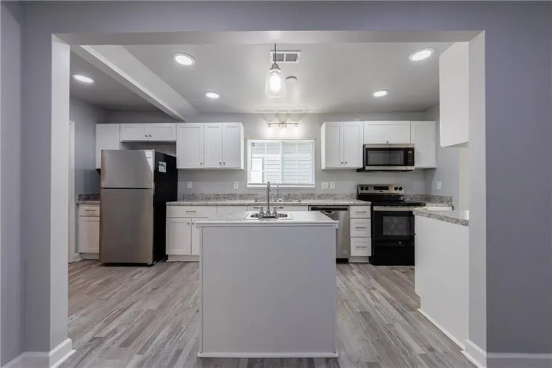 Kitchen with white cabinets, stainless steel appliances, and light wood-style floors