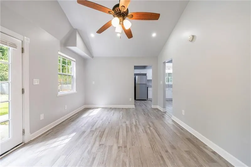 Unfurnished living room with baseboards, recessed lighting, light wood finished floors, a ceiling fan, and high vaulted ceiling