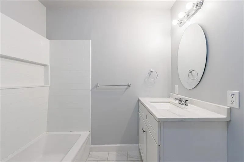 Full bathroom with vanity,  shower combination, marble finish floor, and baseboards