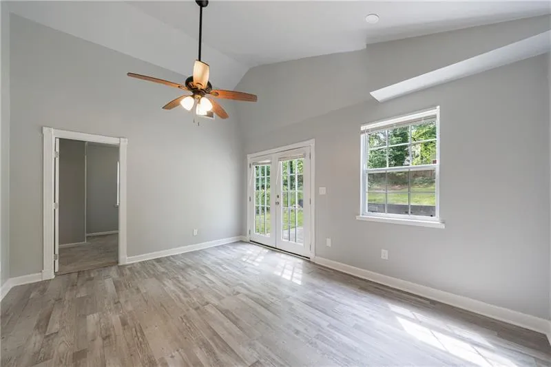 Unfurnished room featuring baseboards, high vaulted ceiling, ceiling fan, and light wood-style floors