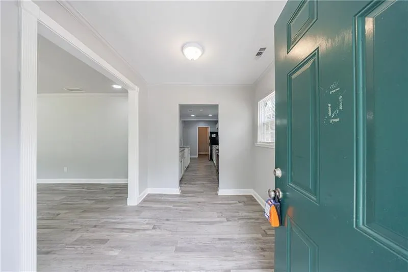 Foyer entrance featuring baseboards, visible vents, crown molding, and light wood finished floors