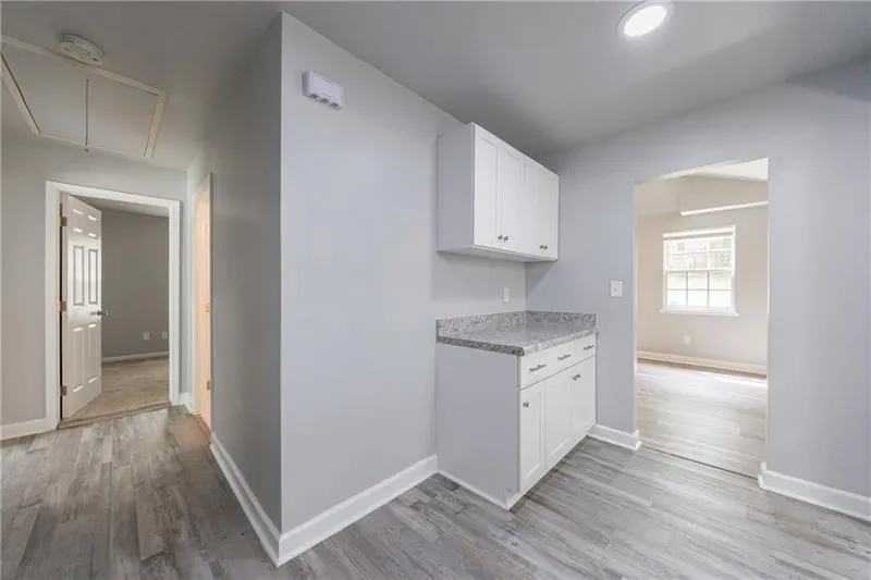 Kitchen with baseboards, white cabinets, light wood finished floors, and light countertops