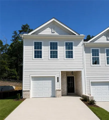 Modern townhome exterior featuring light-colored siding, a prominent front-facing gable, and an integrated single-car garage