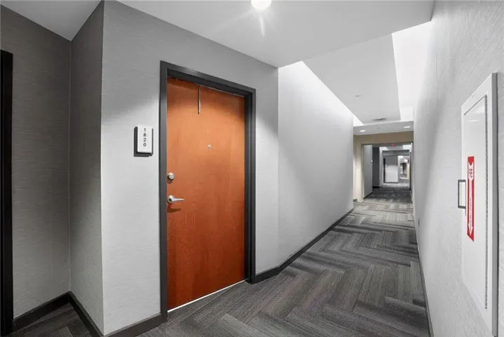 Hall with dark carpet and a textured wall