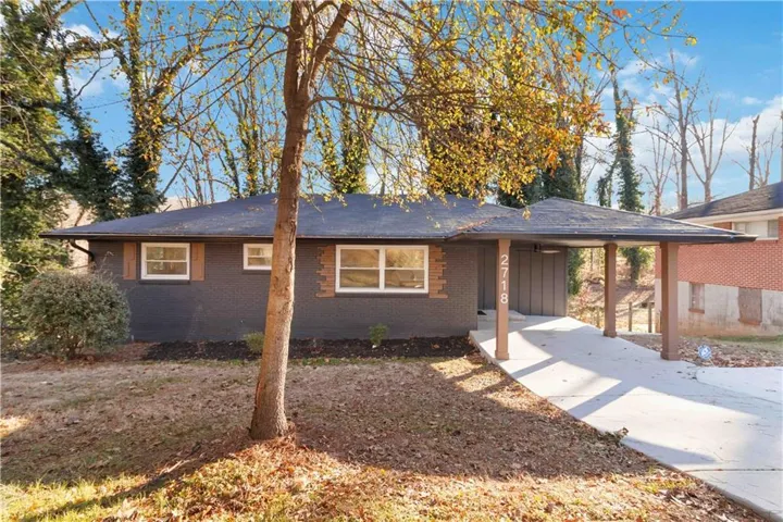 View of front of home featuring an attached carport, brick siding, and concrete driveway