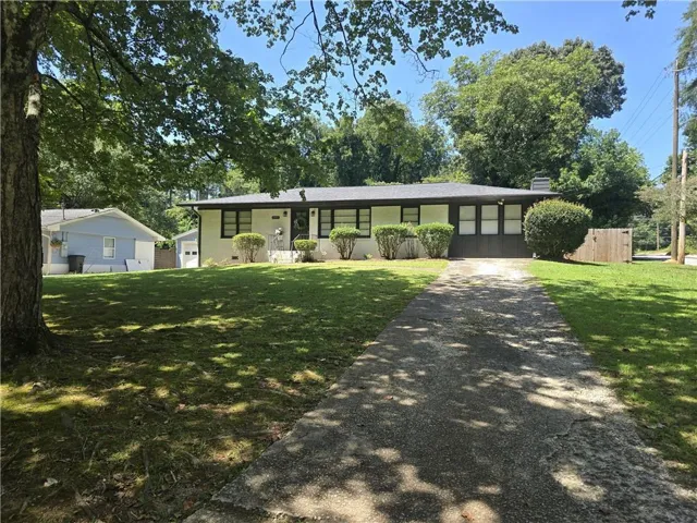 Ranch-style exterior with a dark shingle roof, white brick facade, and dark trim windows