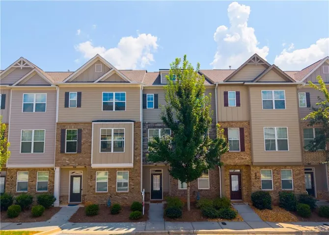 Three-story townhome with a brick and siding facade, individual entry, and front landscaping