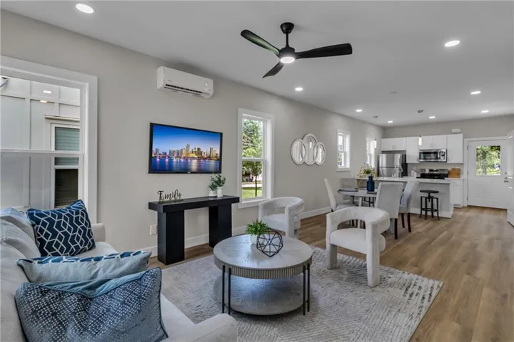 Open-concept living space featuring wood-finish flooring, recessed lighting, and multiple windows