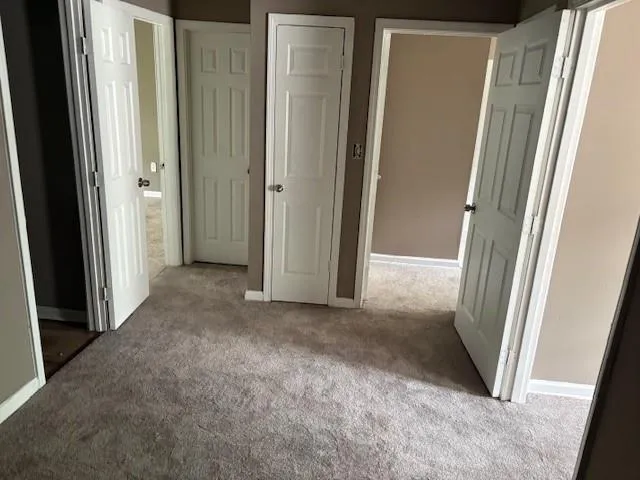 Unfurnished bedroom with carpet flooring and baseboards