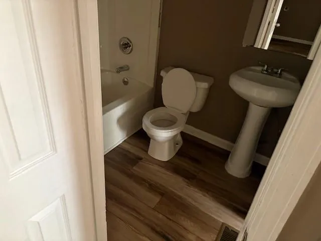Bathroom with wood finished floors and shower / tub combination