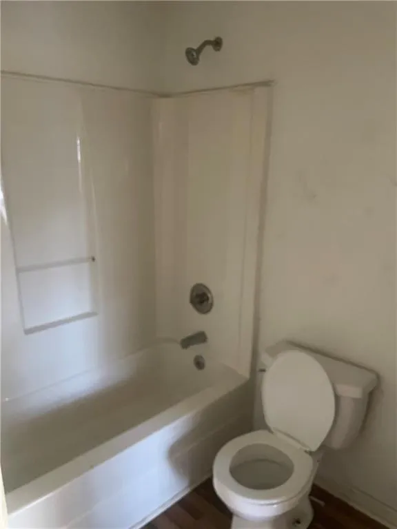Bathroom featuring toilet, wood-type flooring, and shower / tub combination