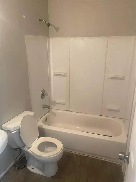 Bathroom with toilet, wood-type flooring, and tub / shower combination