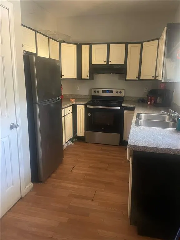 Kitchen with white cabinets, wood-type flooring, stainless steel appliances, and sink