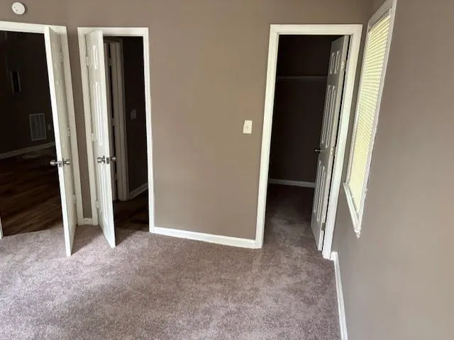 Unfurnished bedroom featuring a spacious closet and carpet floors