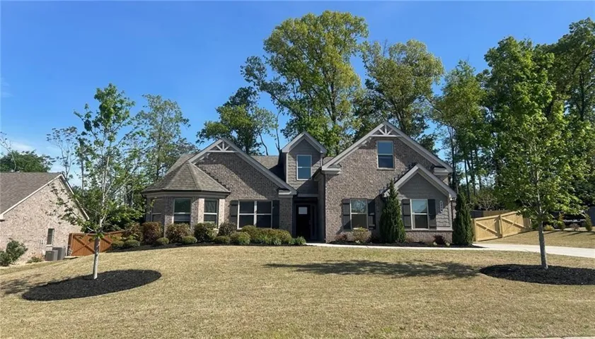 Brick and siding exterior with gabled roof lines, featuring a rounded bay window and mature landscaping