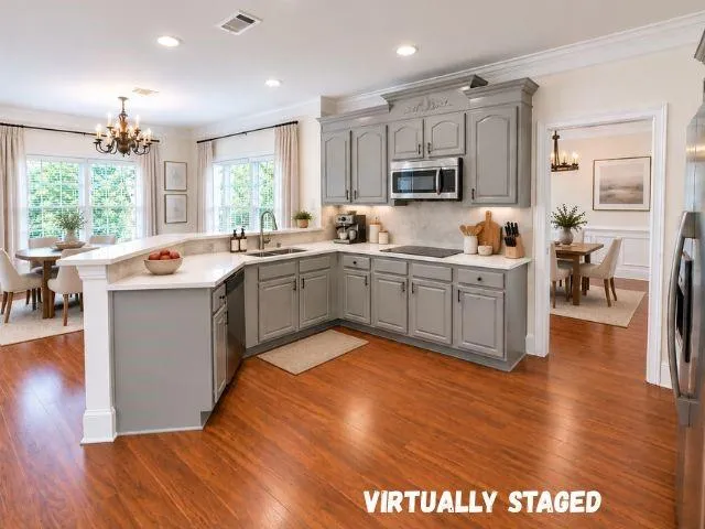 Kitchen featuring wood-finish flooring, gray cabinetry, stainless steel appliances, and light countertops